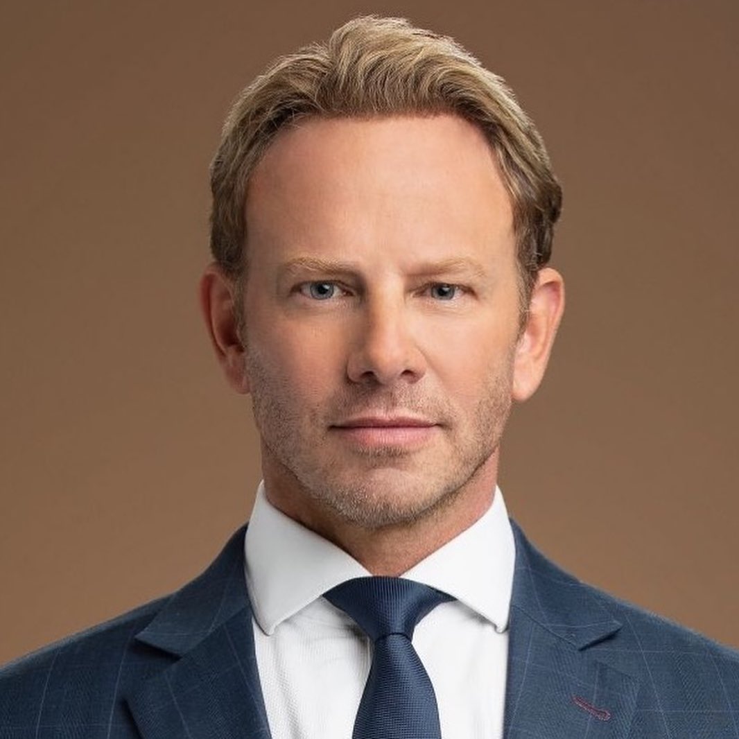 A photo showing Ian Ziering in a blue striped suit paired with a white inner T-shirt and blue tie.