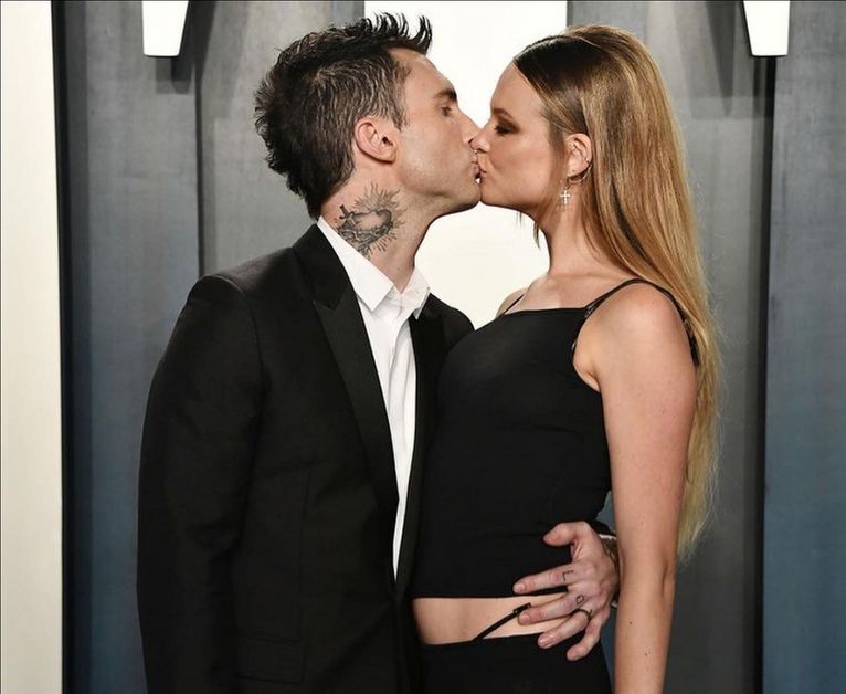 Behati and Adam Levin kissing on red carpet