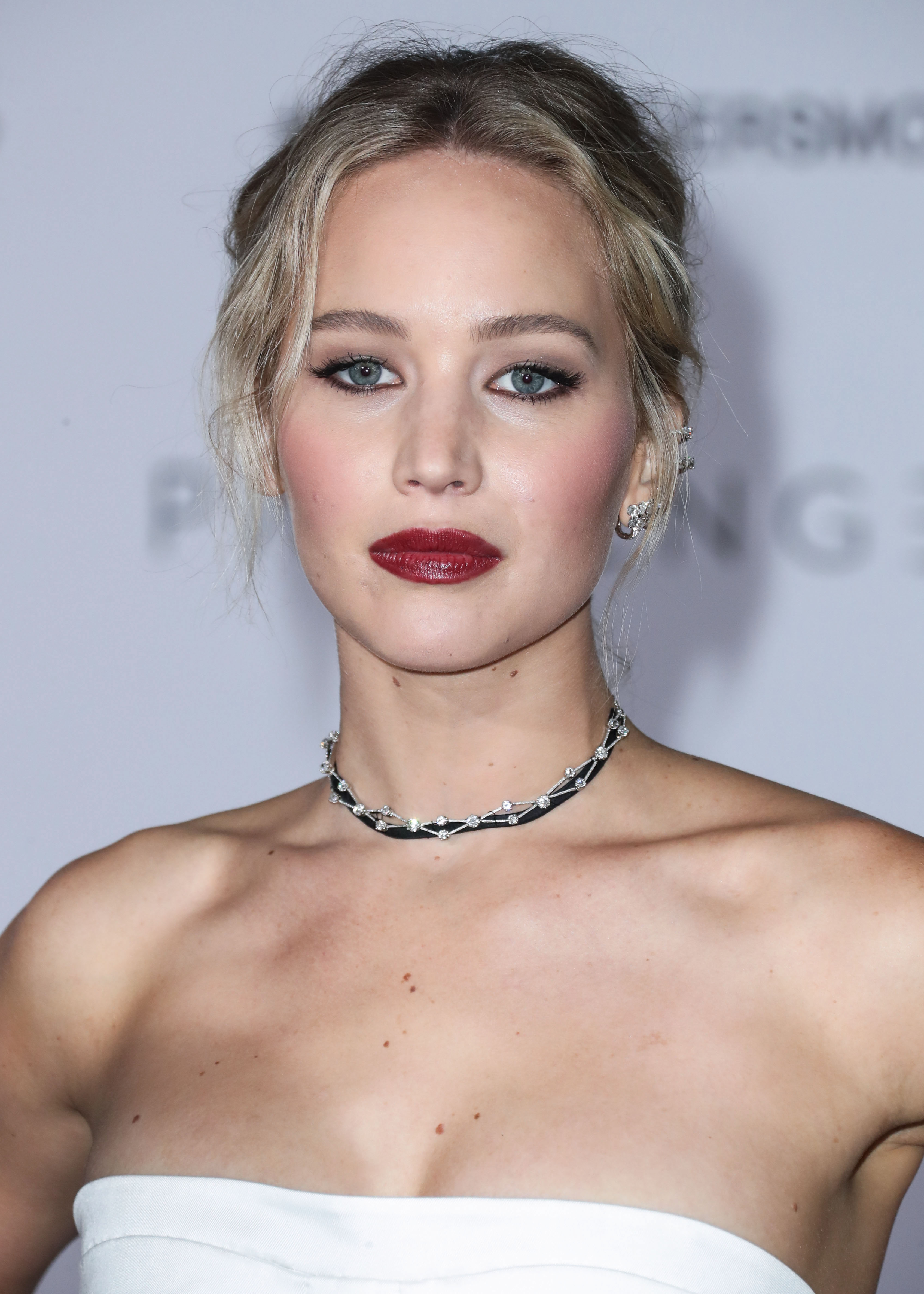 A beautiful looking Jennifer Lawrence seen in a white armless dress, paired with a unique choker and earrings.