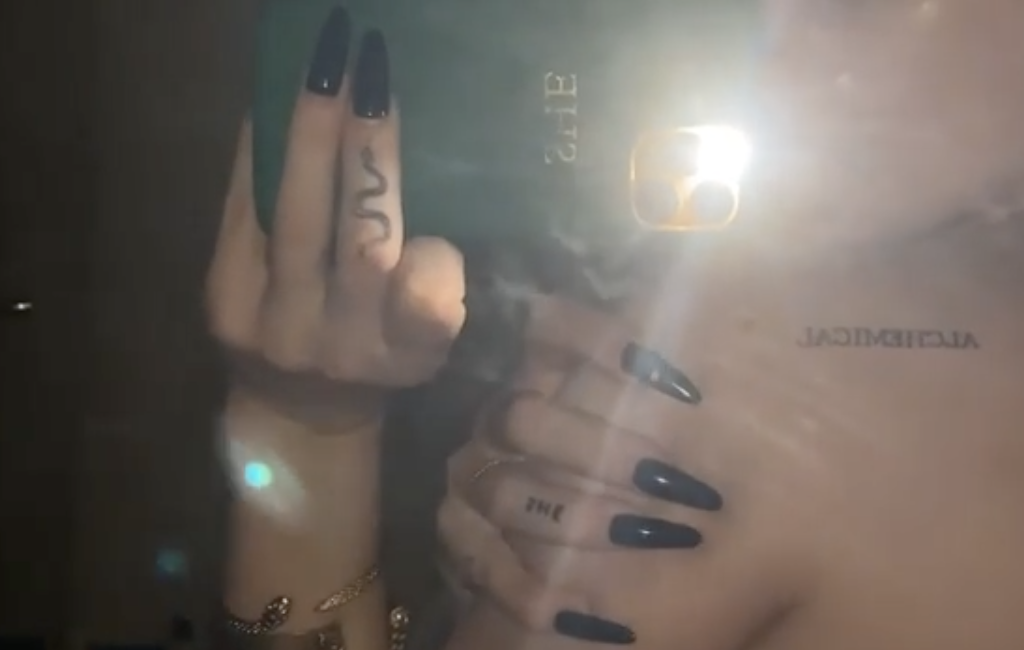 Dove Cameron doing a mirror video selfie while topless and showing her new tattoo.