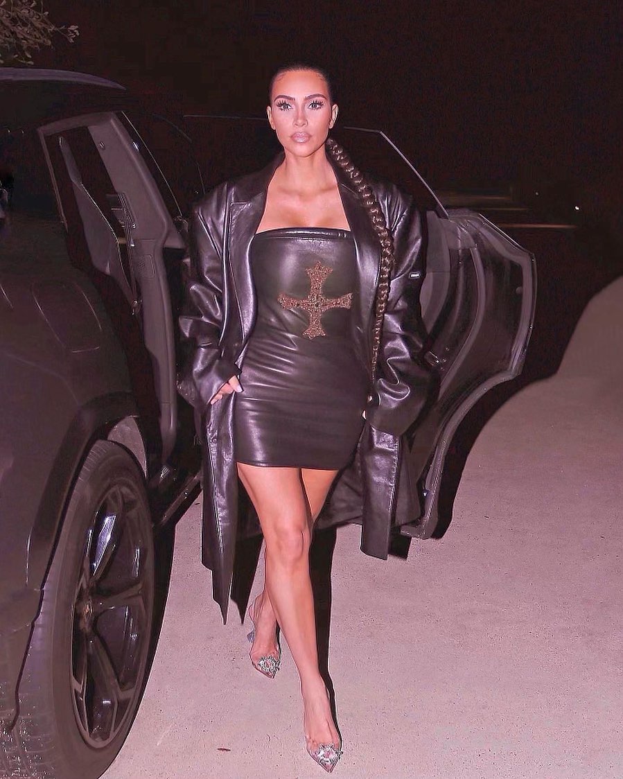 An awesome photo of Kim Kardashian in a black leather jacket and body-con black dress, stepping out of a black vehicle.