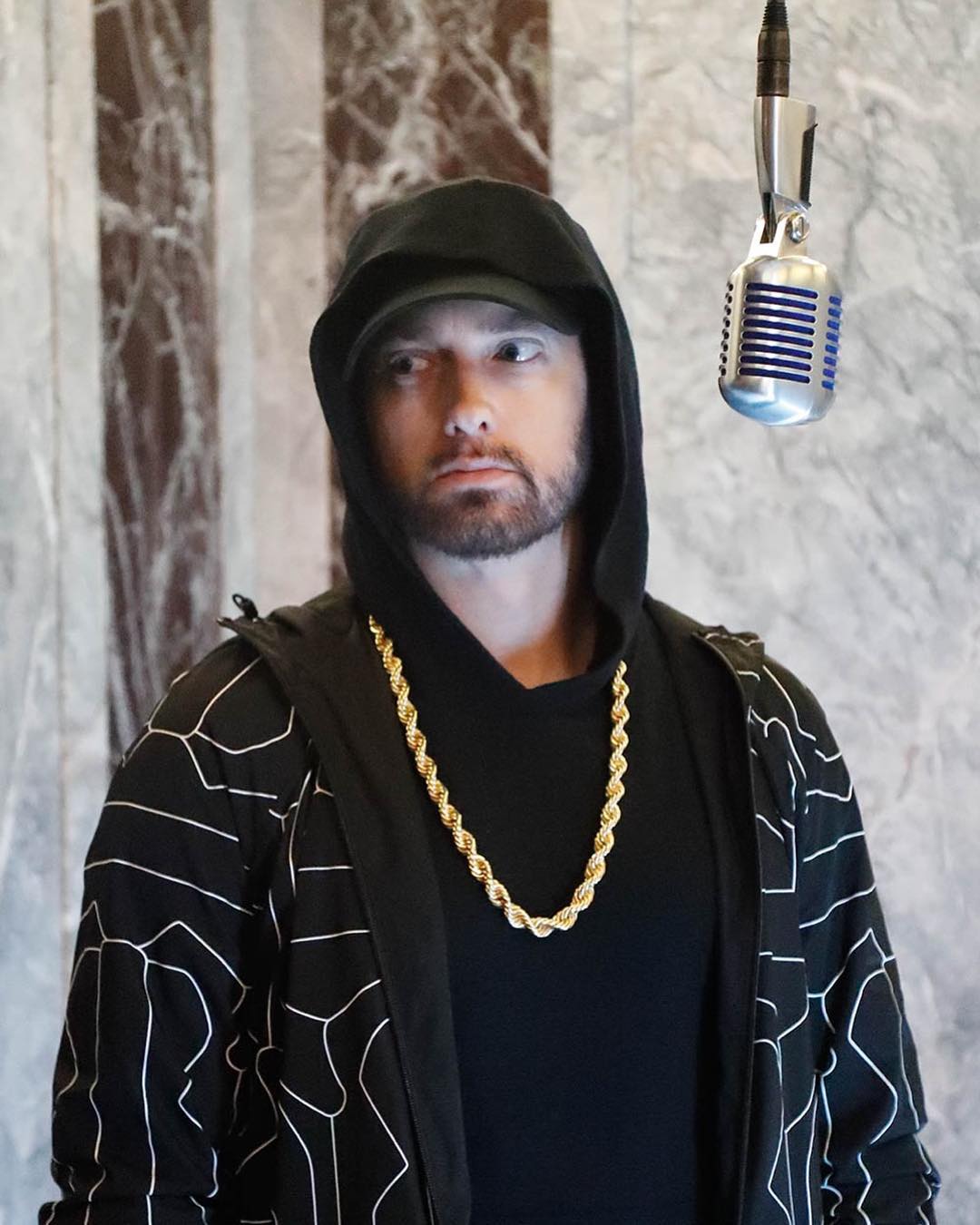 Eminem captured on camera looking sideways, with a suspended microphone in front of him.