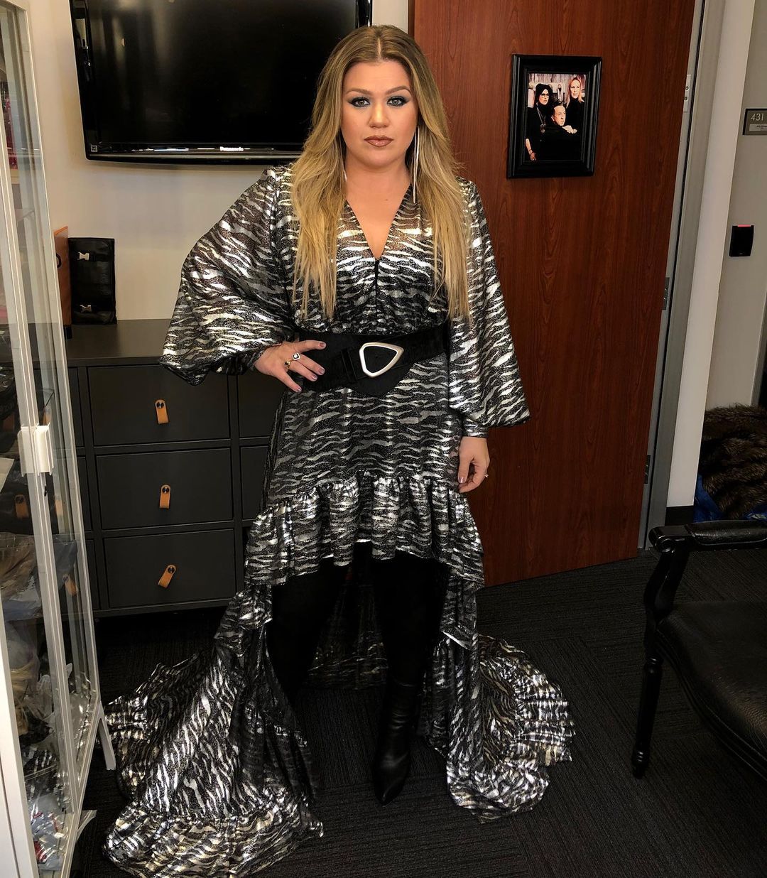 An amazing photo of Kelly Clarkson in a black and white design dress with a belly belt and boots to match.