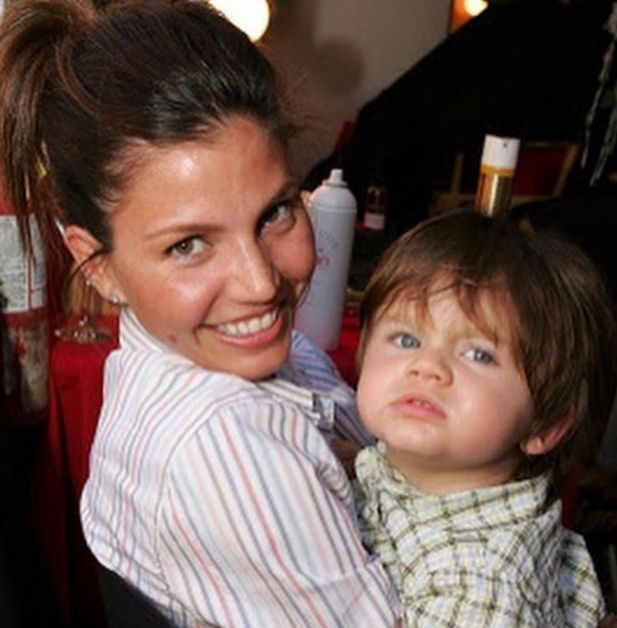 Charisma Carpenter smiles for the camera as she holds her baby son in her arms.