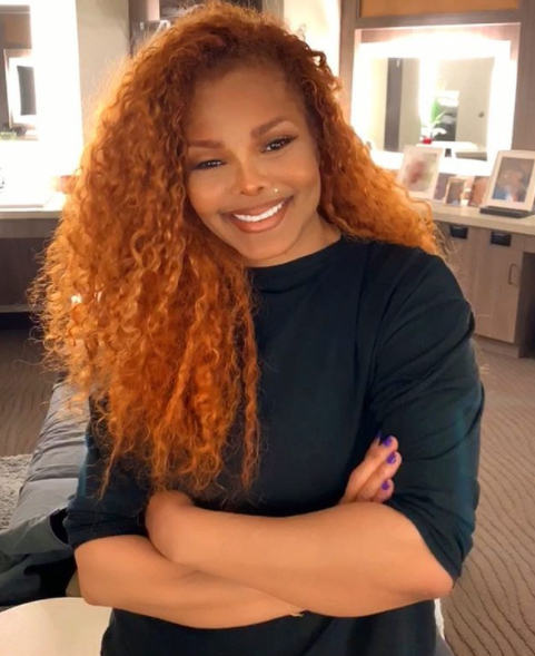 Janet Jackson smiling with red curly hair
