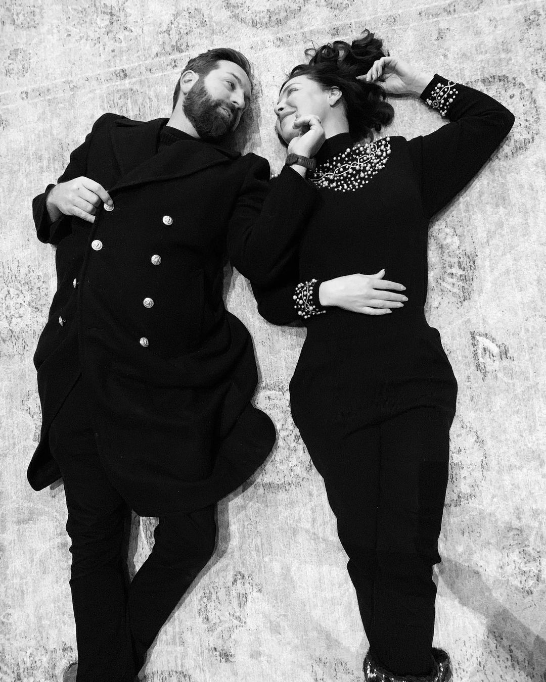 A black and white themed photo featuring Katherine Heigl and her husband, Josh Kelley lying on a ground and staring at each other intently.