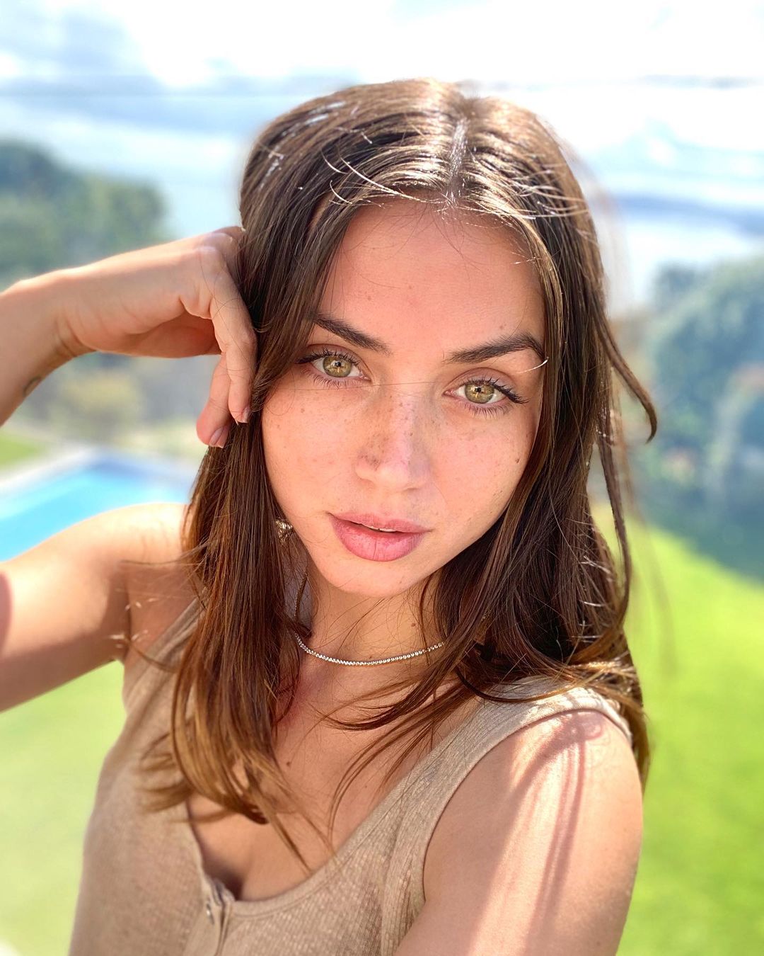 A lovely photo showing the make-up free Ana de Armas side a pool and green field and she looks amazing.
