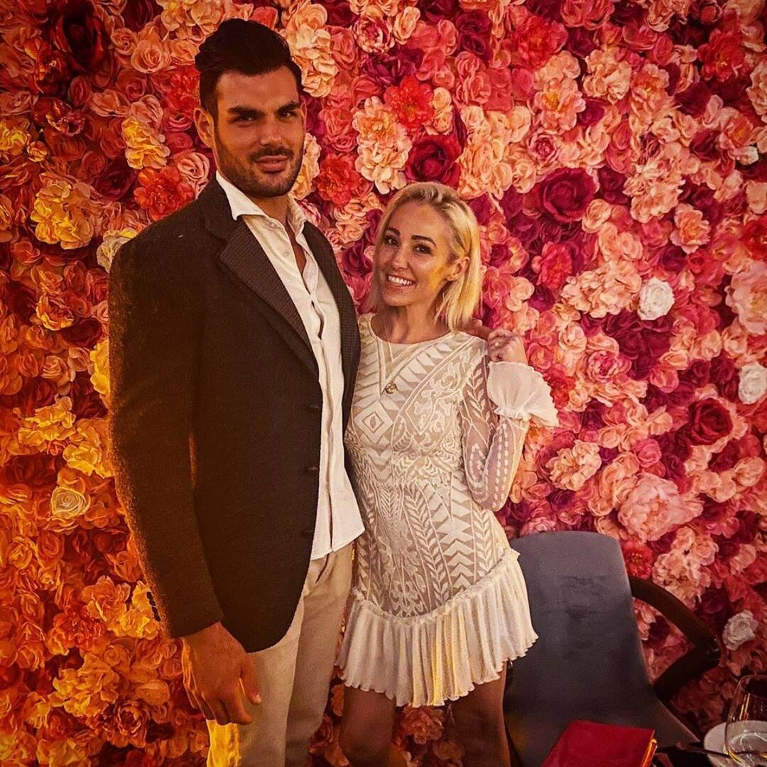 Mary Fitzgerald and husband Romain stand in front of red and pink roses.