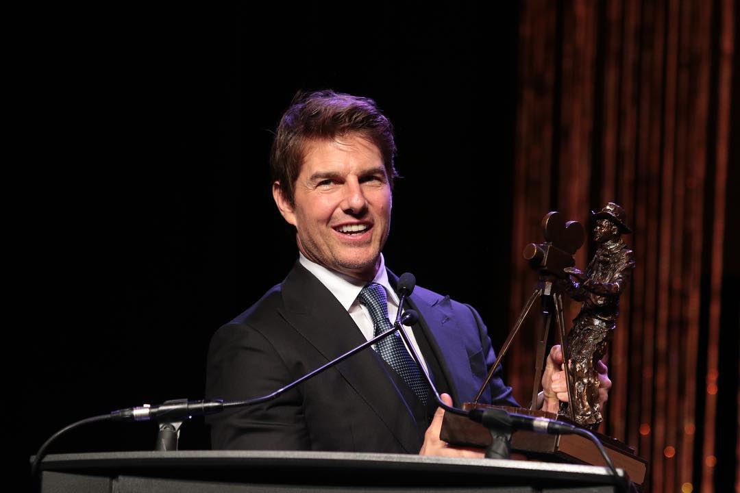 A throwback photo showing Tom Cruise holding an award with a smile on his face as he gives a speech.