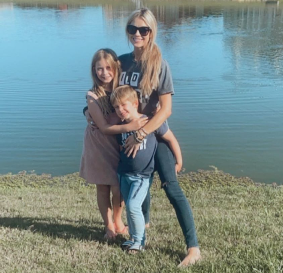 Christina Anstead poses with her kids in front of a lake.