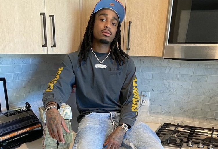 Quavo in his kitchen with stacks of cash.