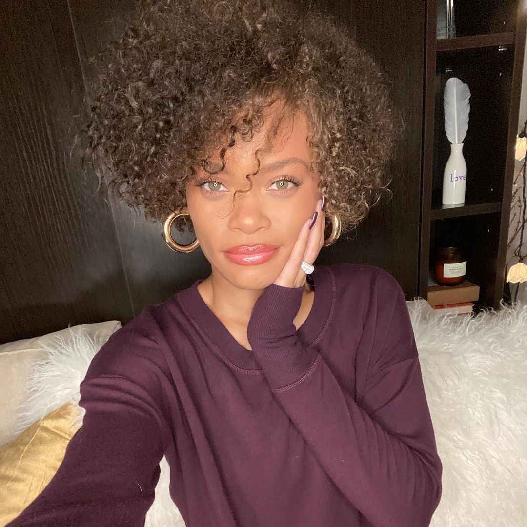 Andra Day looks gorgeous in this photo showing her sitting in a purple sweatshirt and she looks amazing.