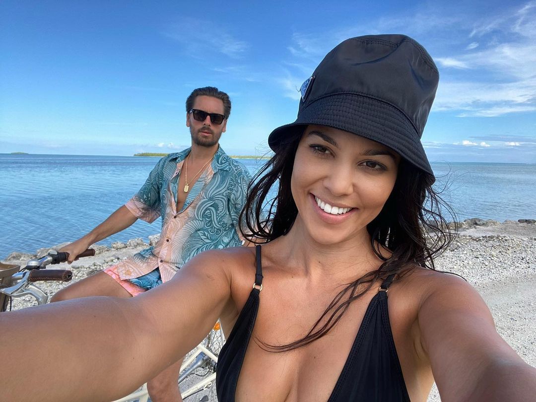 A photo showing Kourtney Kardashian taking a selfie with Scott Disick at a beach area with blue waters.