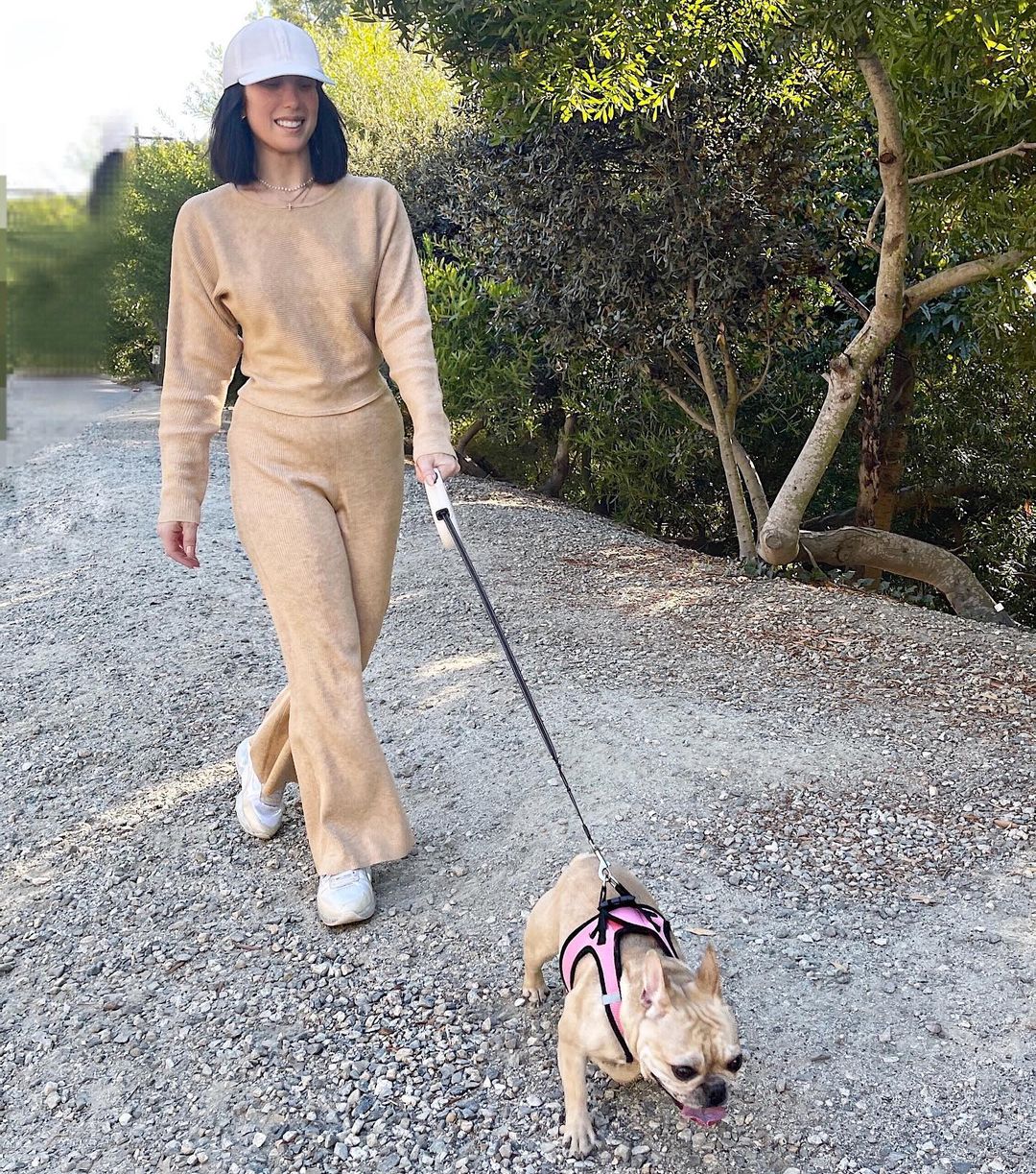 A photo showing Cheryl Burke walking her dog through a path and they look amazing in matching colors.