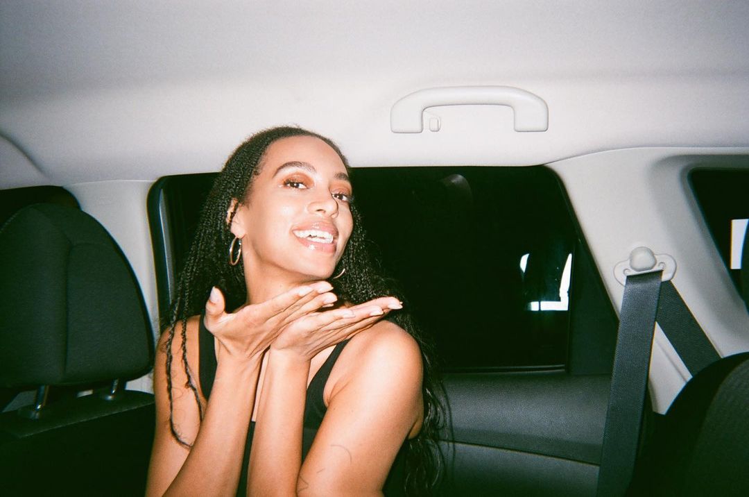 A photo of Solange Knowles posing for the camera in a vehicle with an excited look on her face.