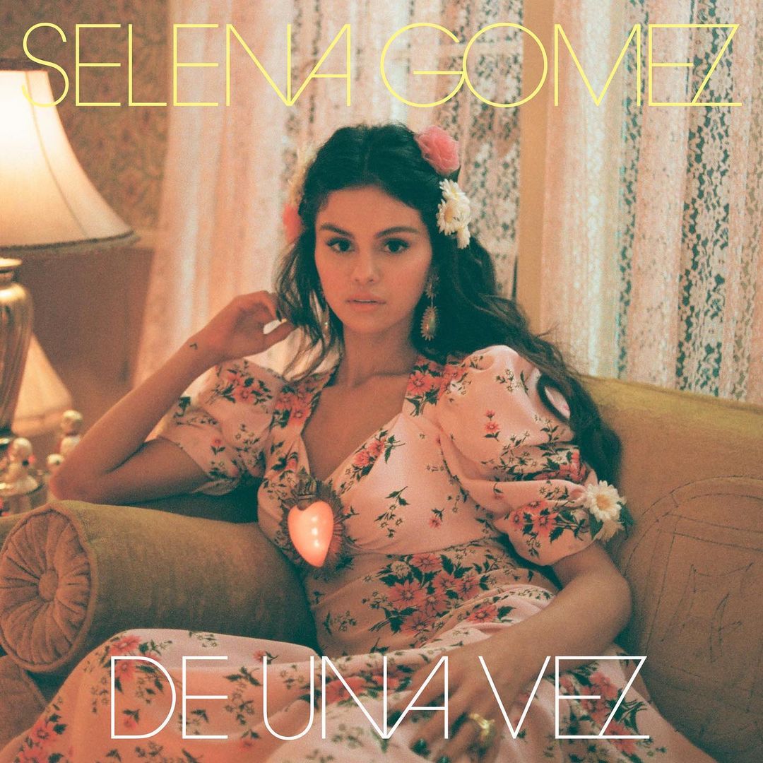 The cover of Selena Gomez's latest single De Una Vez and it shows her wearing a lovely pink dress with flowery designs.
