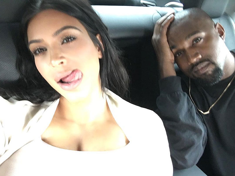 Kim Kardashian and Kanye West taking a selfie in the backseat of a car