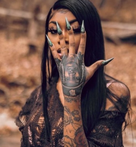 Doll showing off her King Von tattoo on her hand.