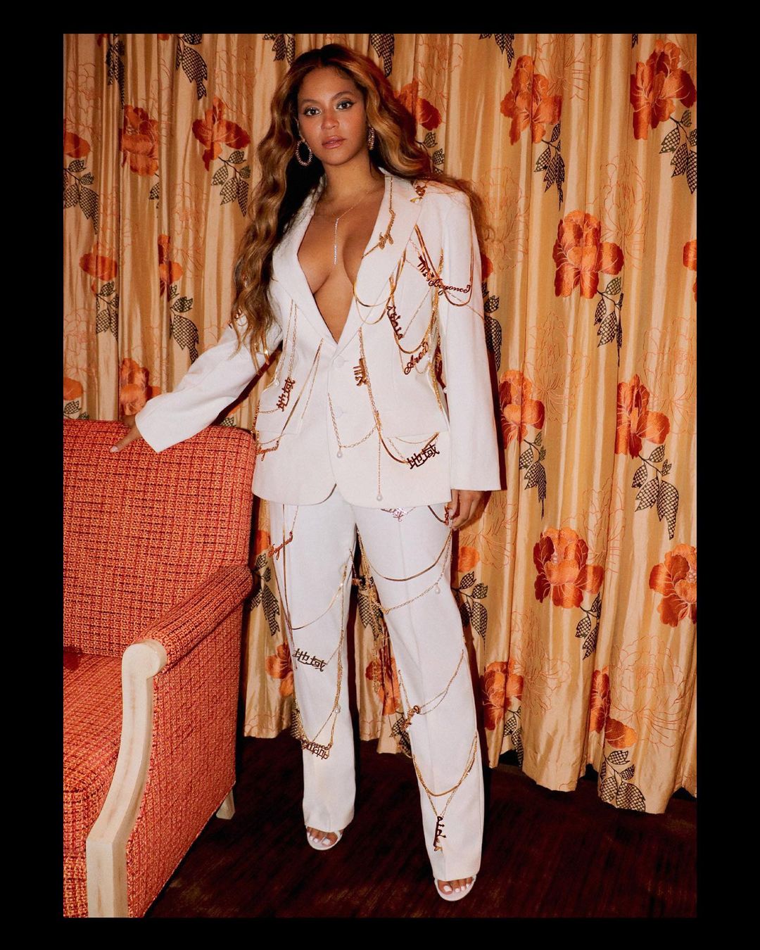 Beyoncé Knowles looks amazing in this white two-piece outfit with gold chains all over it.