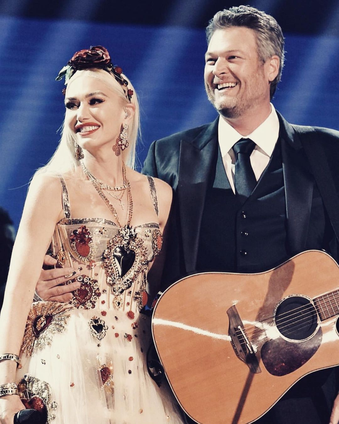 A picture of Gwen Stefani and fiance Blake Shelton together on stage looking happy after a performance.