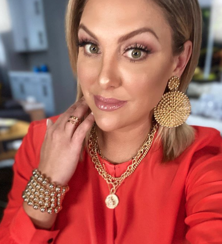 Gina Kirschenheiter wears large gold earrings and a red shirt.