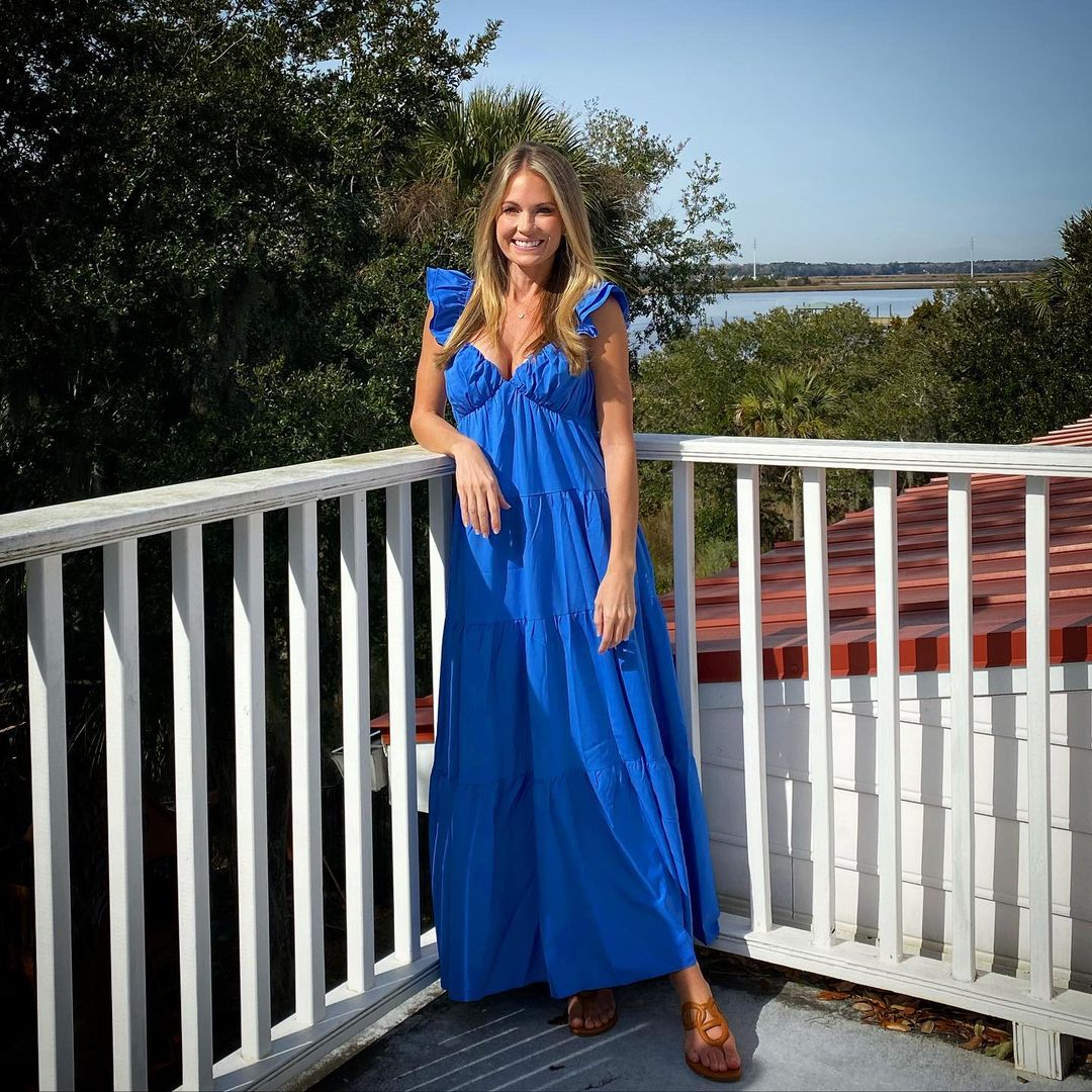 A lovely photo showing Cameran Eubanks out on her porch, dressed in a blue maxi dress paired with a low brown footwear.