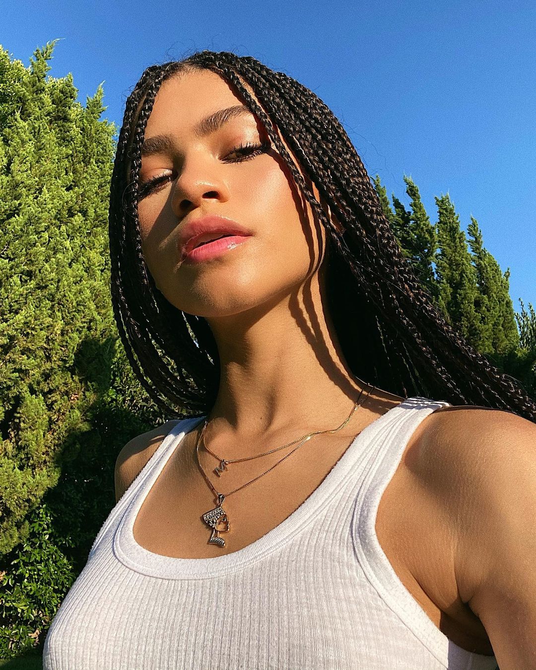 Zendaya soaking up the sun in a white tank-top and braids.