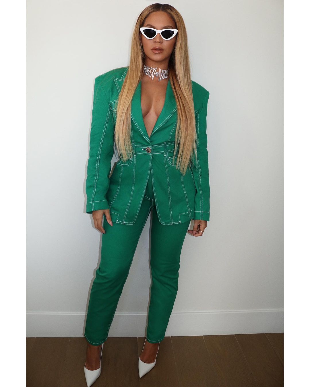 A lovely photo showing Beyoncé in a green two-piece outfit, paired with white heel pumps, a silver choker and white color sun-shades.