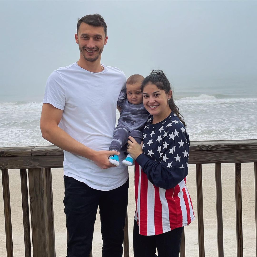 A photo of Loren and Alexei Brovarnik and their son, Shai visiting the beach in casual outfits.