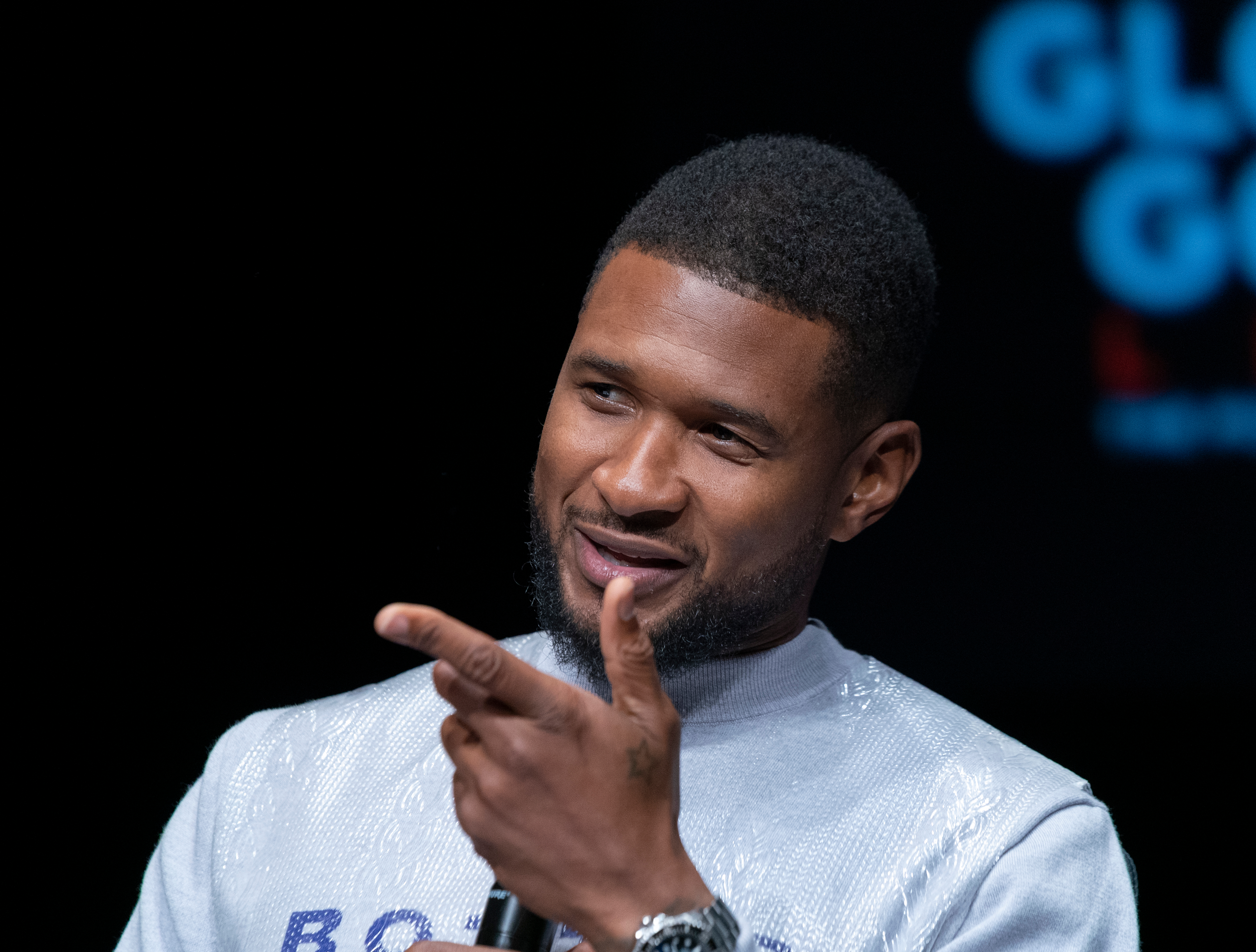 Usher looks incredible in this photo showing him in a white outfit and holding a microphone to his lips.