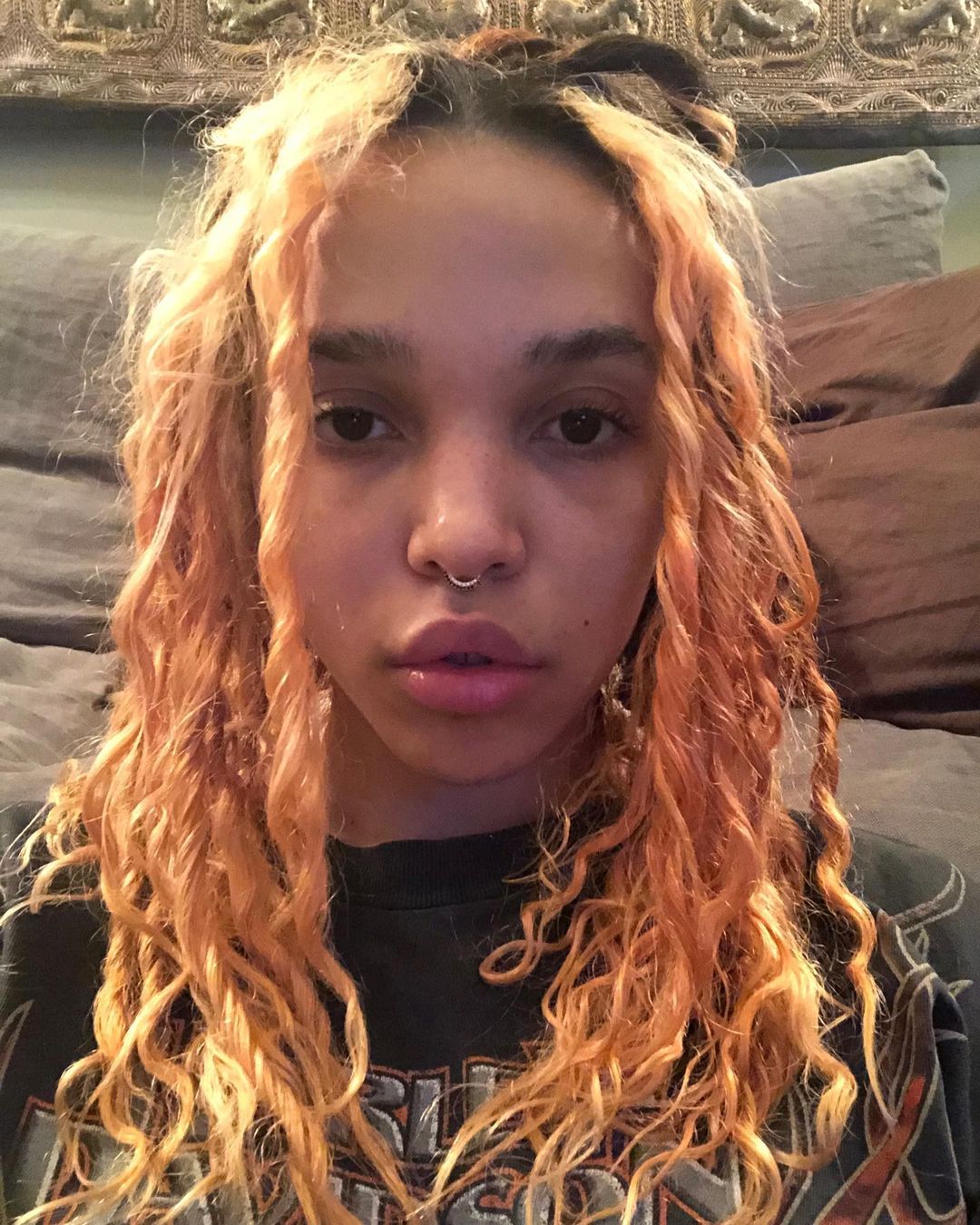 A selfie photo featuring FKA Twigs showing off her roughed gold color air and she has on a black shirt.