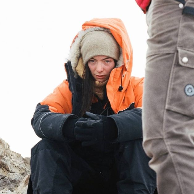 A photo of Lorde bundled up in an orange parka from her recent trip to Antartica. 