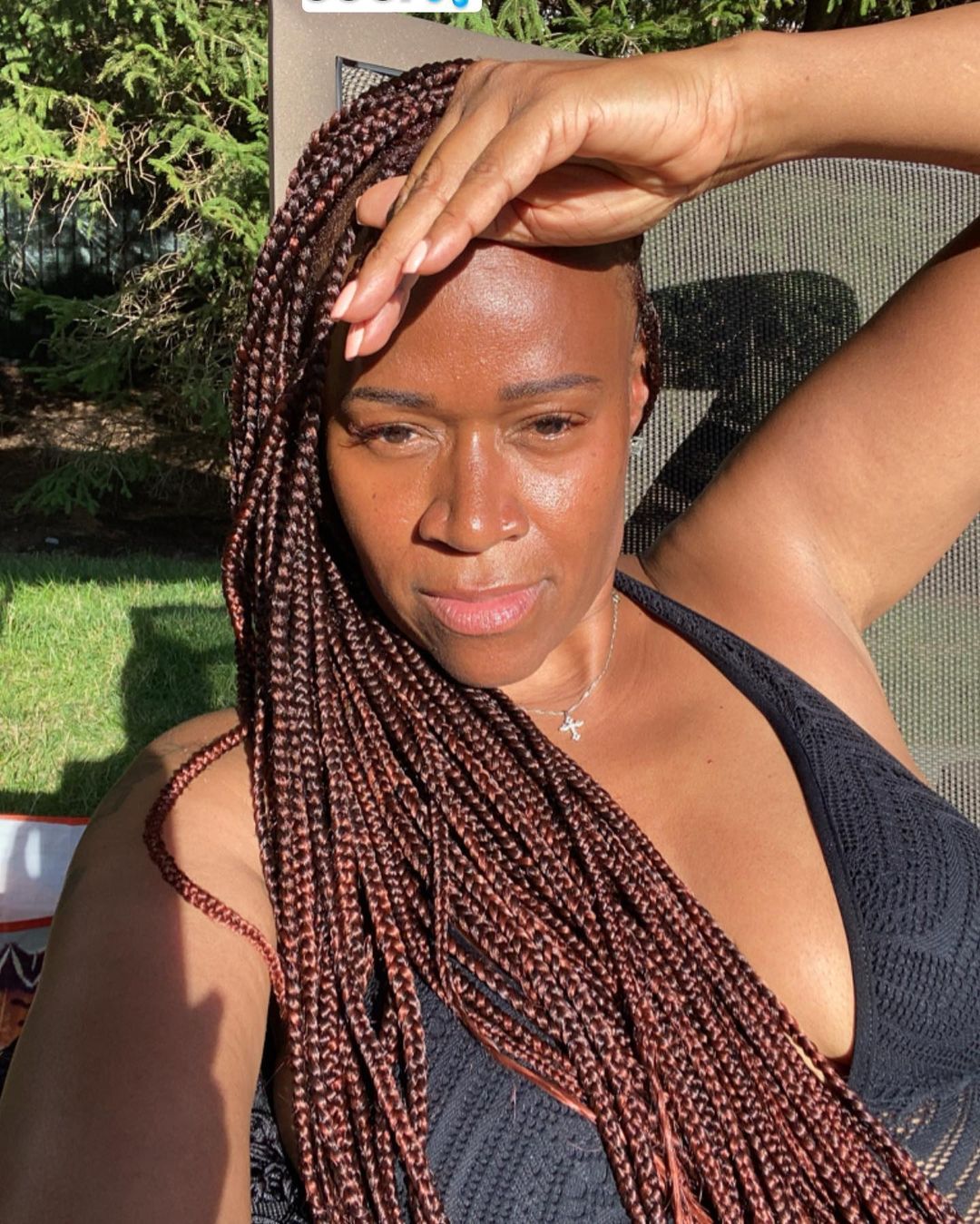 A photo showing Tashera Simmons relaxing outdoors in a black net swimsuit.