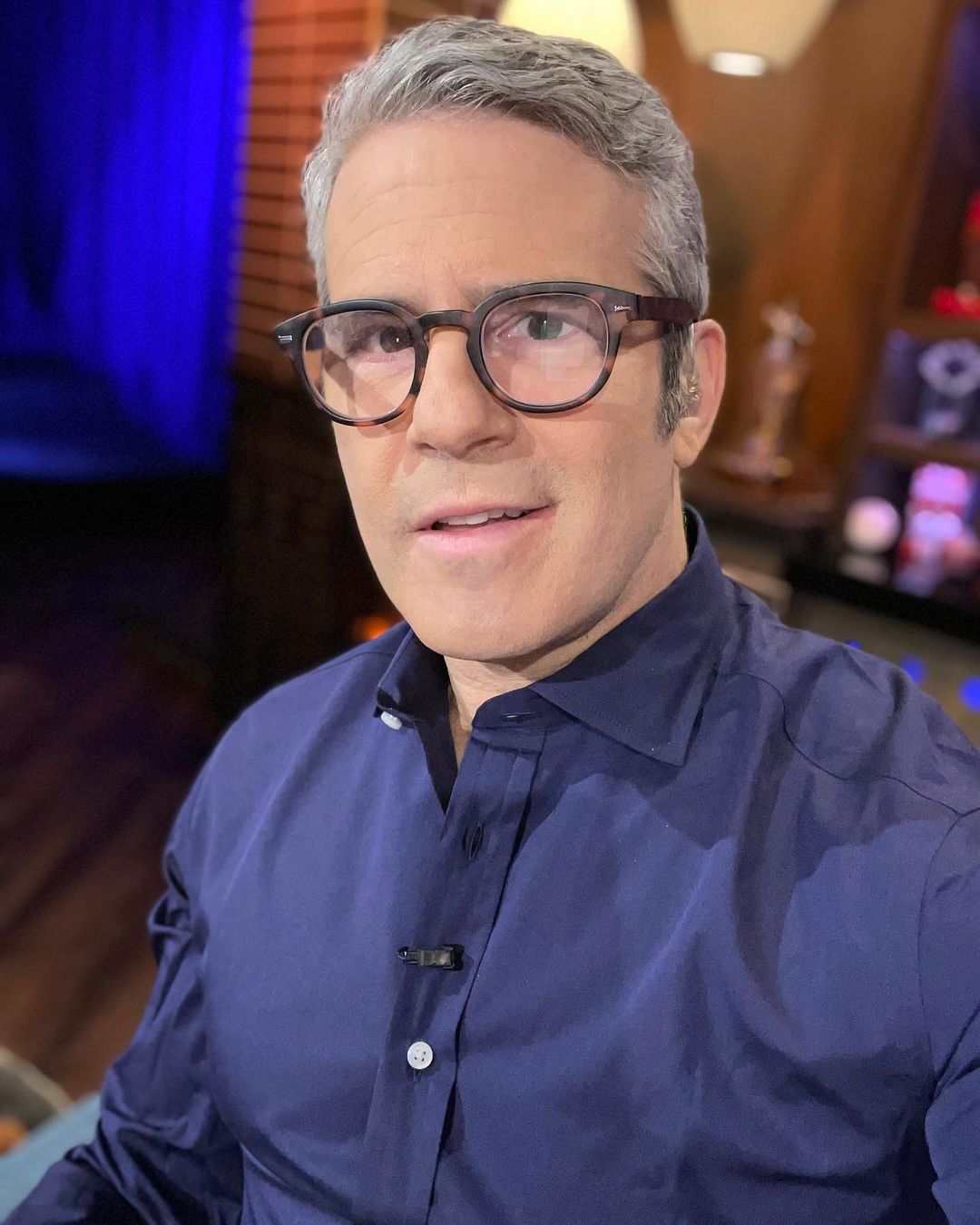 A photo showing Andy Cohen in a blue T-shirt and awesome glasses.