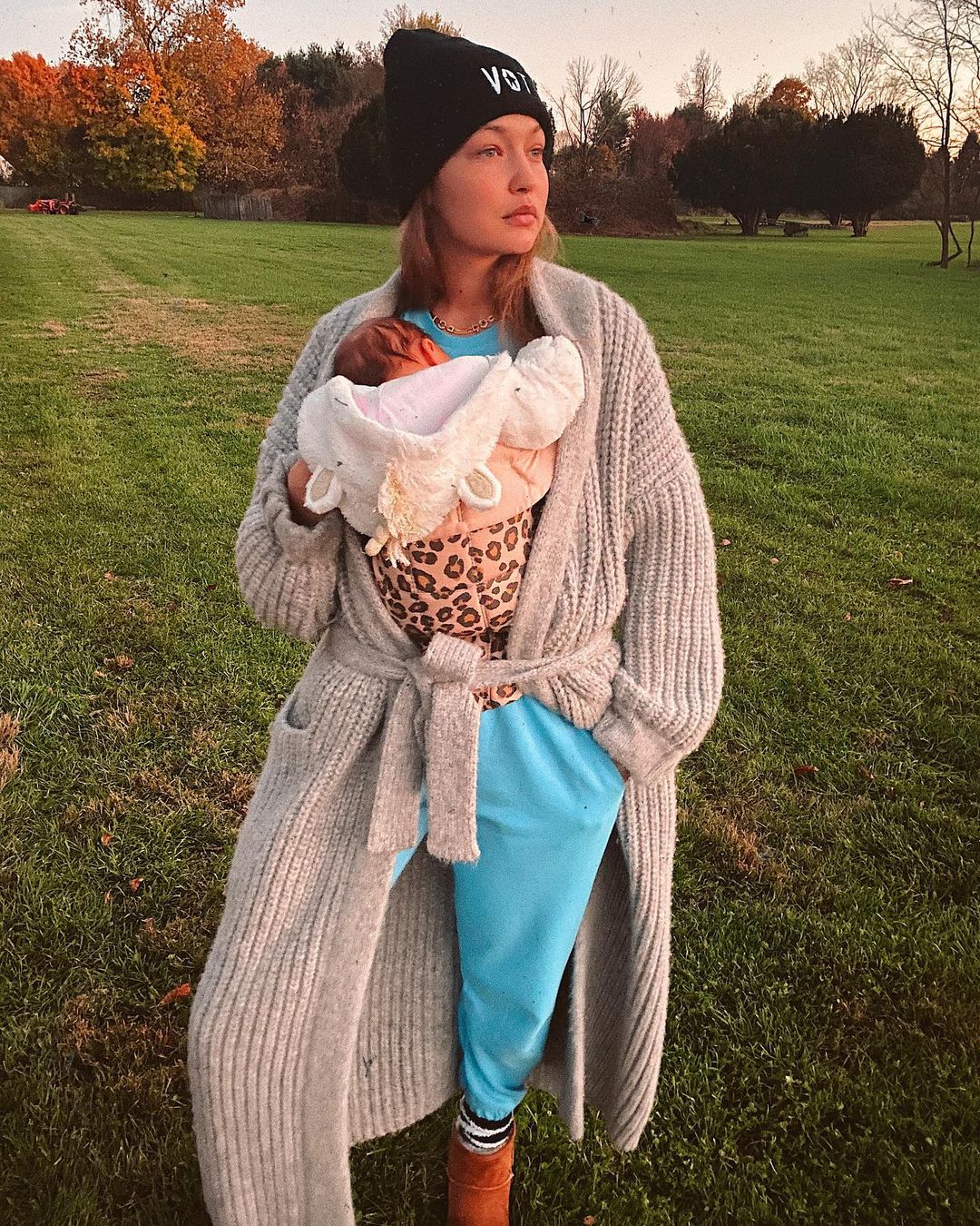 Gigi Hadid looks absolutely gorgeous in this blue two-piece outfit and overall sweater, while holding her bundle of joy to her chest.