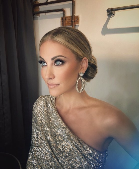 Stephanie Hollman wears hair in a bun with large hoop earrings.