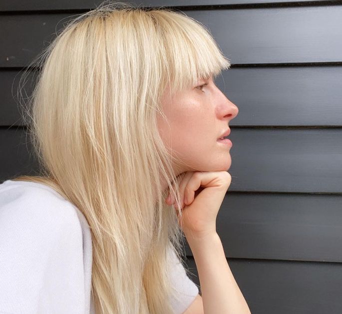 Hayley Williams takes a no-makeup side profile showing off blunt, bleached blonde bangs and long hair.