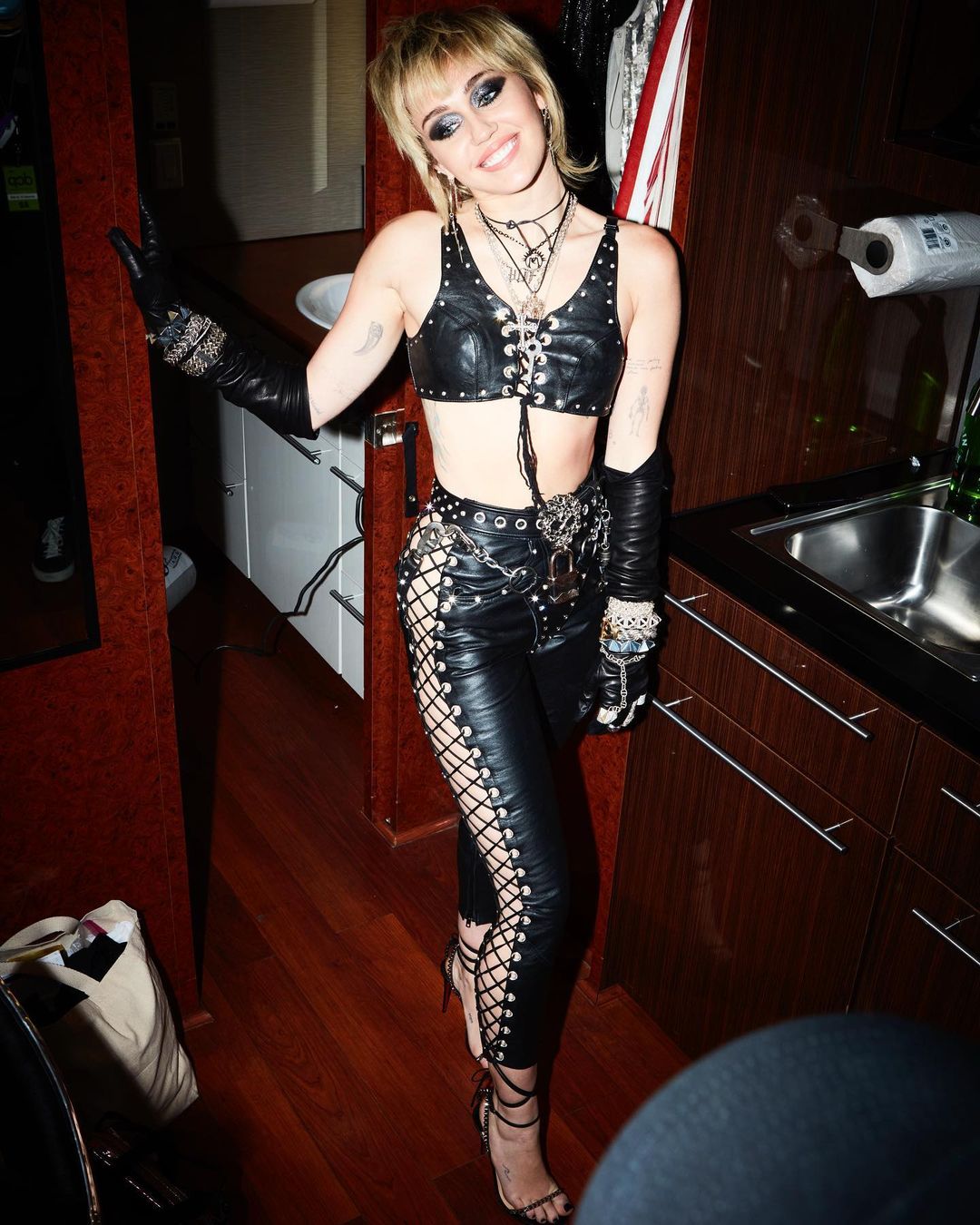 Miley Cyrus looks amazing in this strap leather pant and bra-top, with a sandals heels to match.
