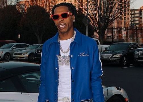 Lil Baby in front of one of his cars.