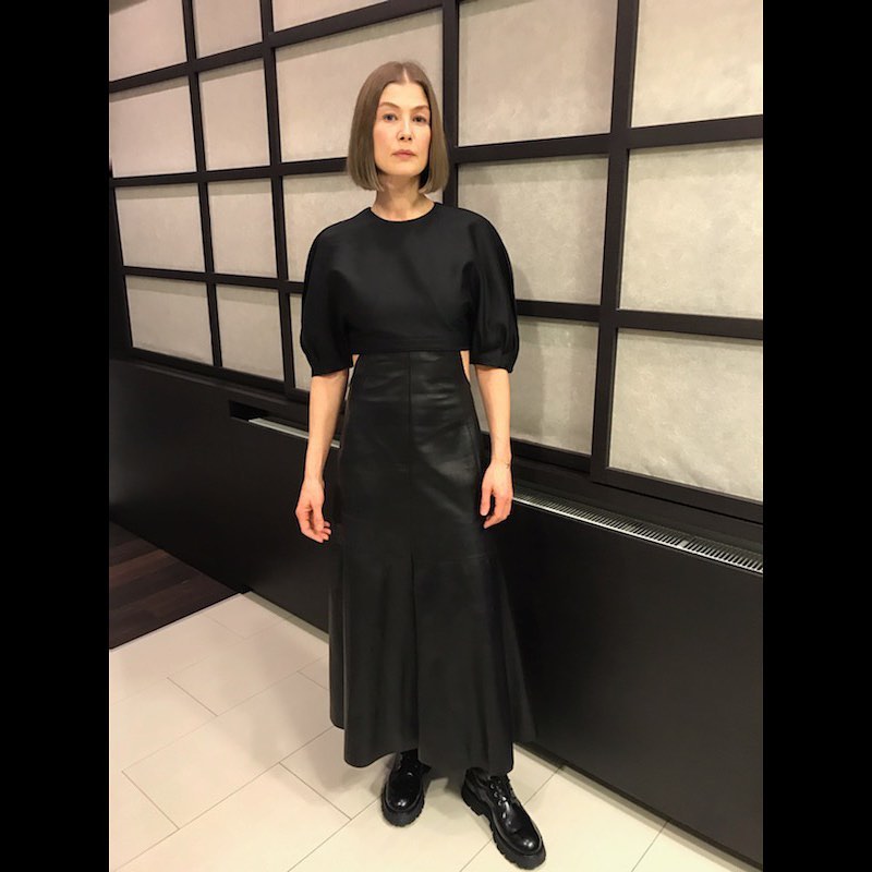 A lovely photo showing Rosamund Pike in a black blouse paired with a long black leather skirt and black boots.