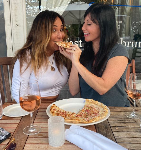 Elyse Slaine feeds pizza to Barbara Kavovit.