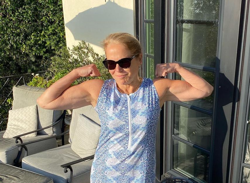 Katie Couric flexes for the camera and shows off her biceps for International Women's Day.