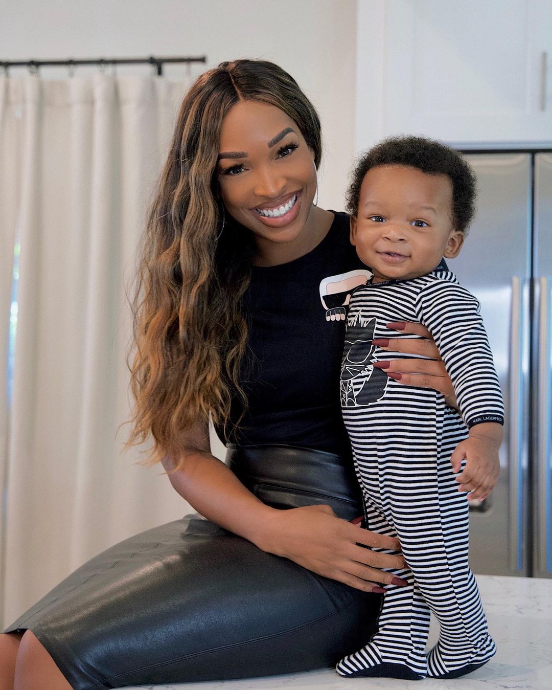 A photo showing Malika Haqq and her son smiling to the camera on the kitchen counter and they look amazing.