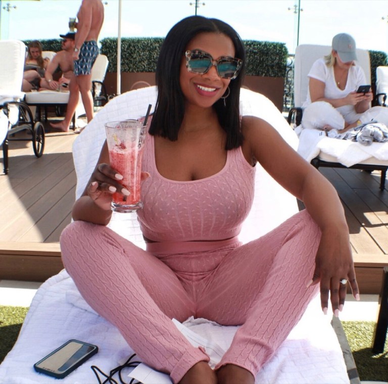 Kandi Burruss wears a pink outfit and enjoys a drink.