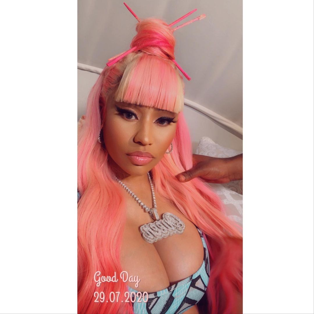 A selfie showing Nicki Minaj checking out her adorable pink hair and she has a huge customized diamond necklace around her neck.