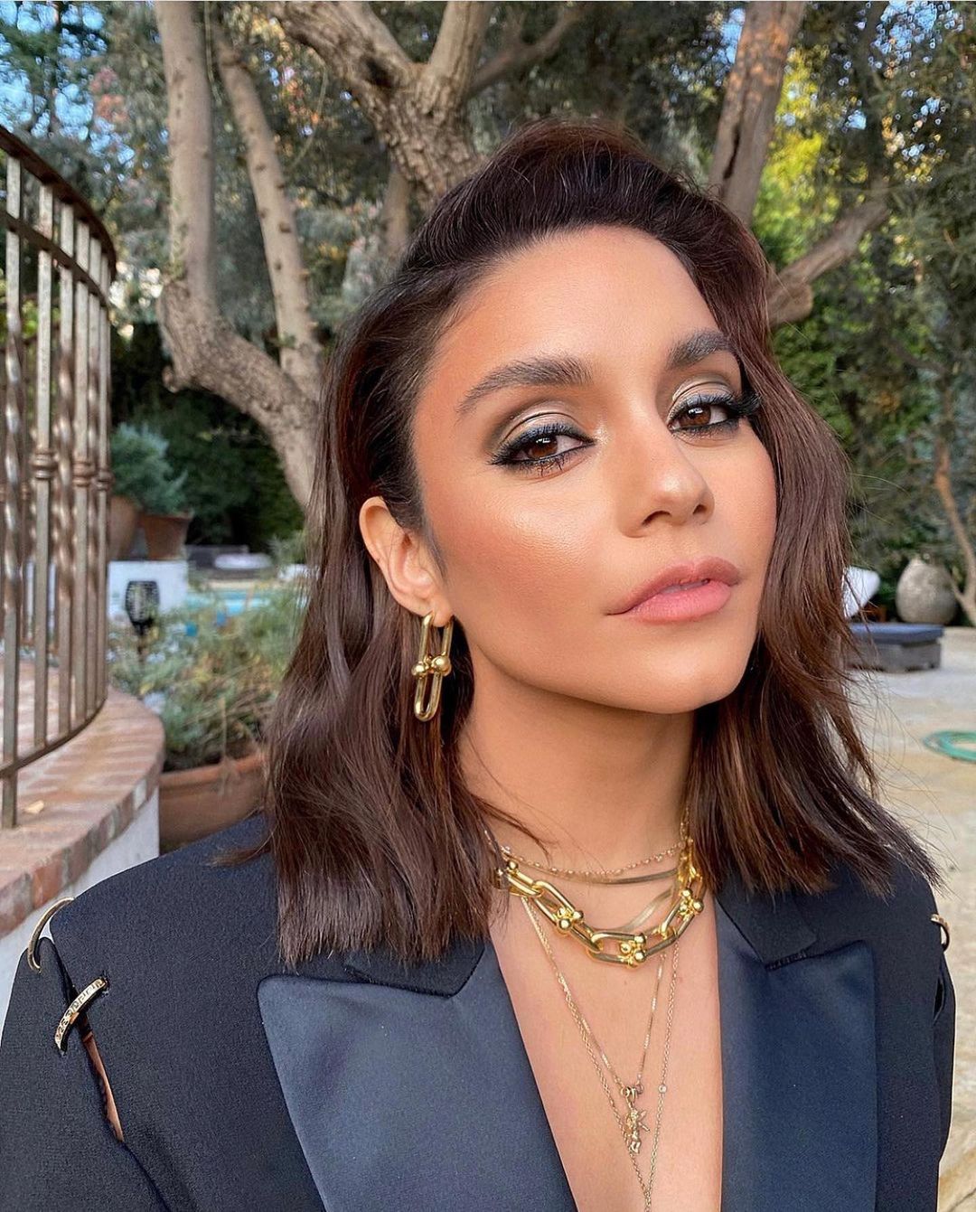 Vanessa Hudgens shows off incredible make-up in this photo, showing her outdoors, sporting a black suit and gold jewelry.