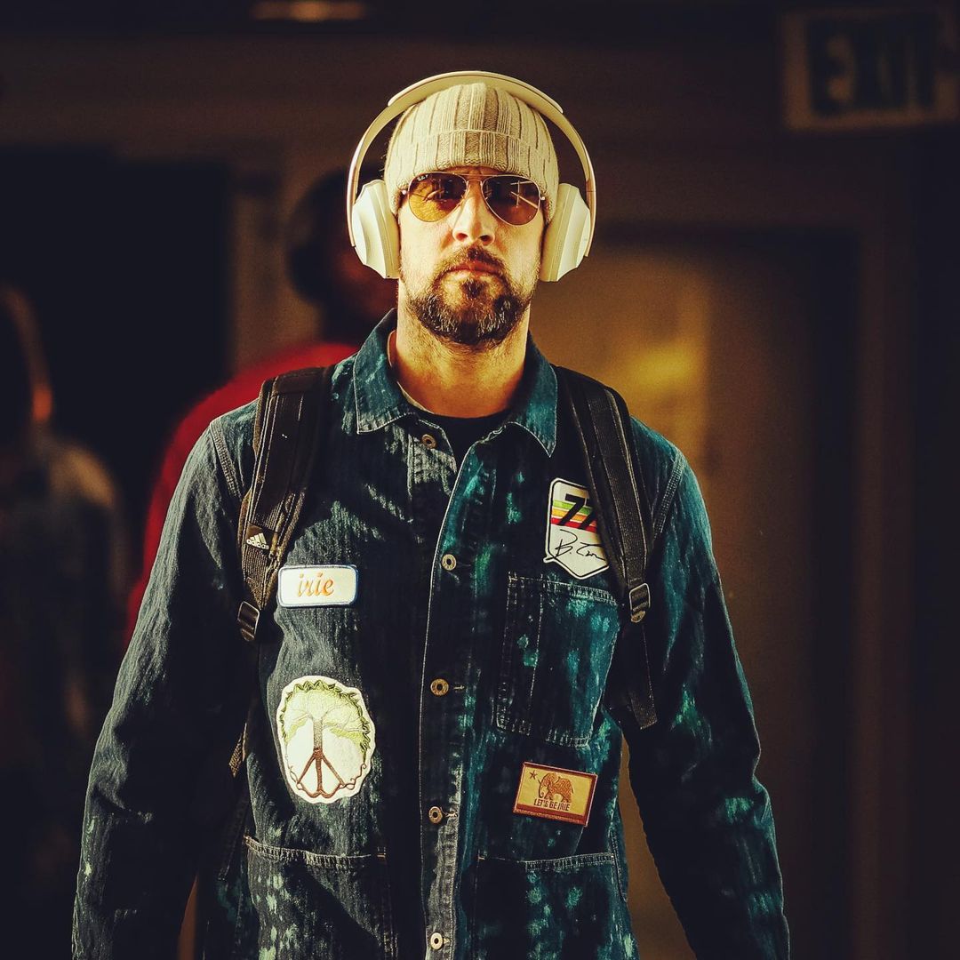 Aaron Rodgers dazzles in this denim design shirt, a head-warmer and backpack, with a headset on his head.