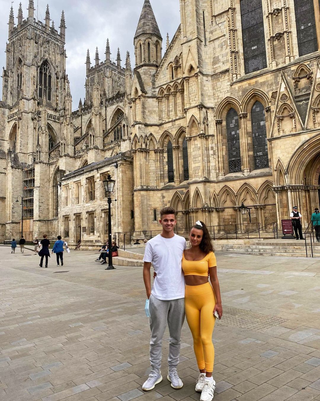 A photo of Joe Warren-Plant and Nichole Hadlow posing on the street in a white and yellow outfit respectively.