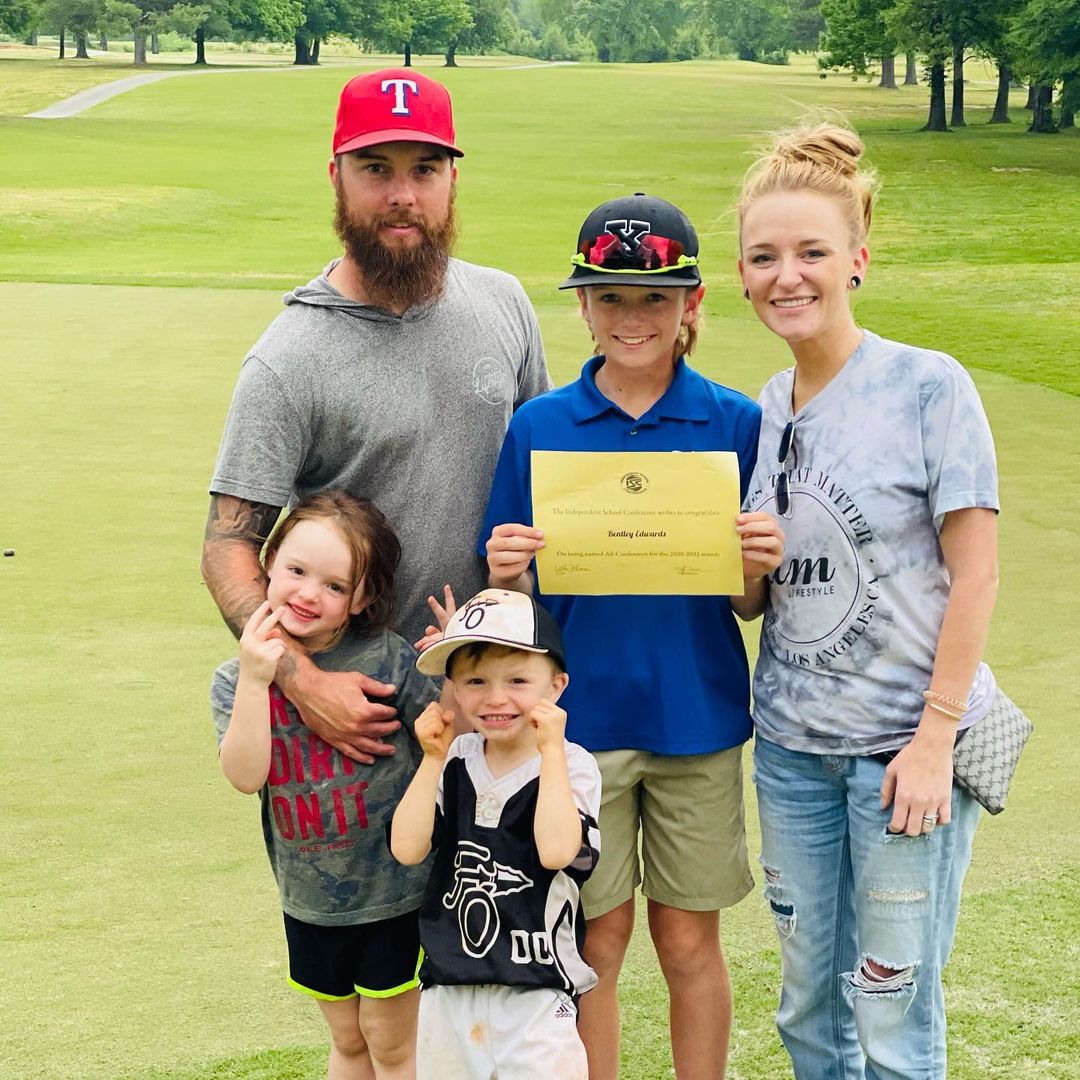 A photo showing Maci Bookout, Taylor McKinney and their lovely three kids, posing for a photo on a large field.