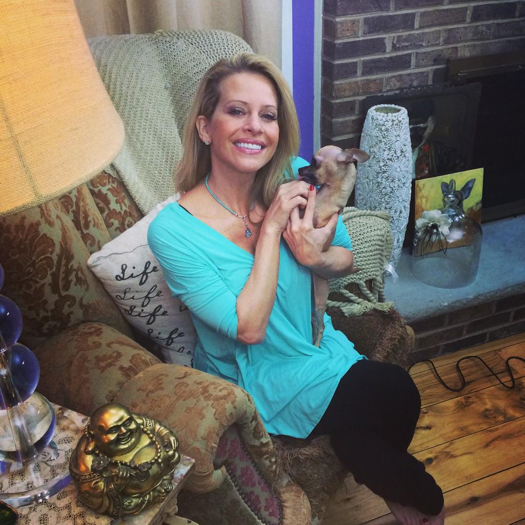 Dina Manzo wears a turquoise shirt and holds a small dog.